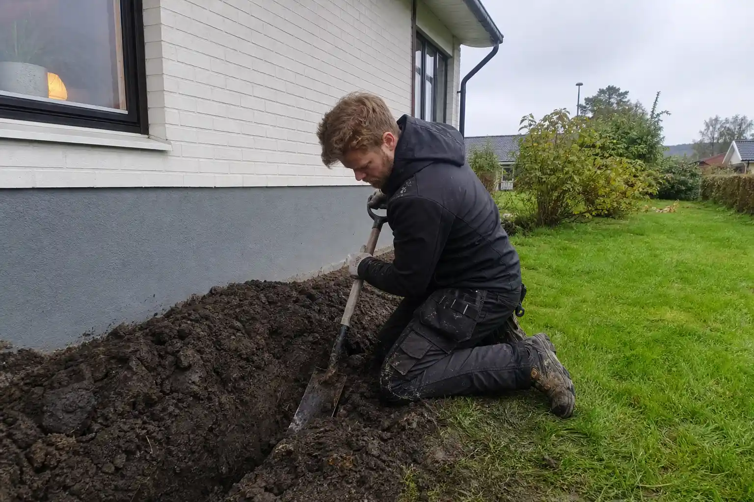 Dräneringsarbete runt husgrund med grävning och rörinläggning