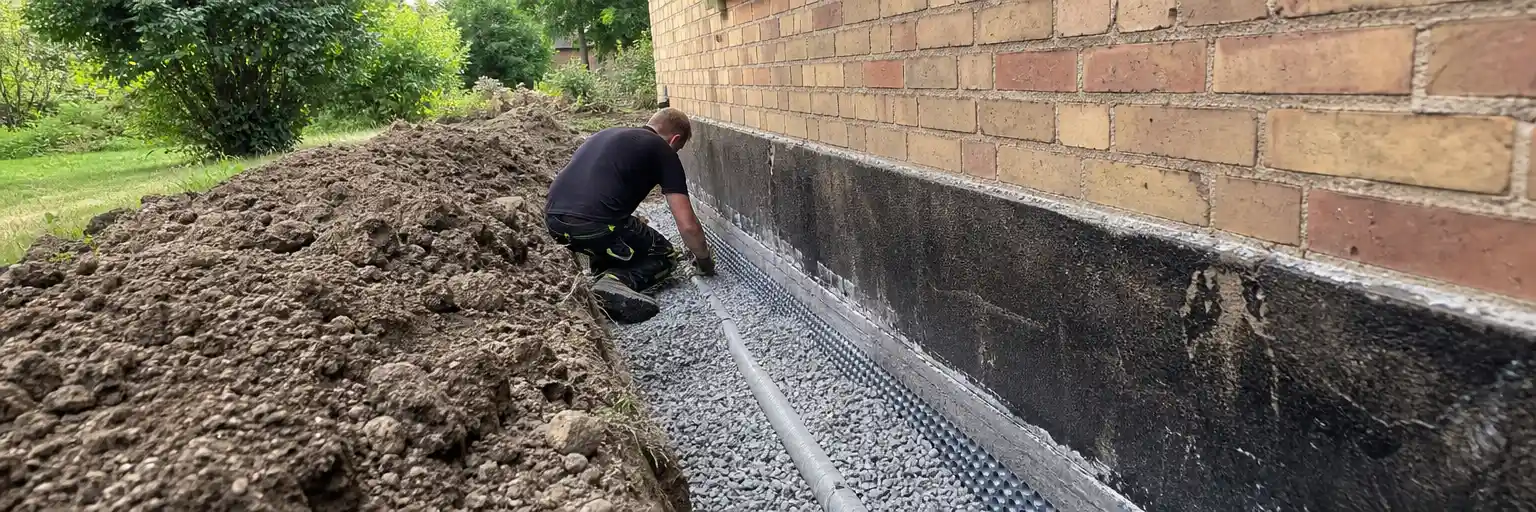 Uppgrävd husgrund vid äldre tegelhus i Lund under dräneringsarbete