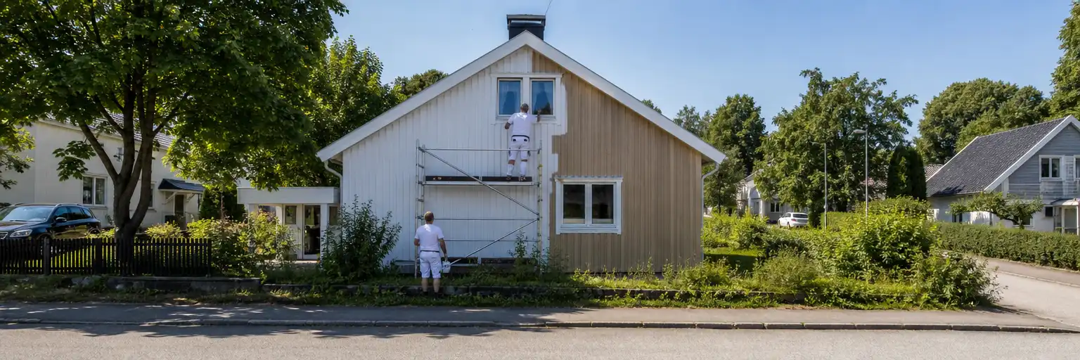 Målare på ställning vid träfasad i villakvarter i Hässleholm