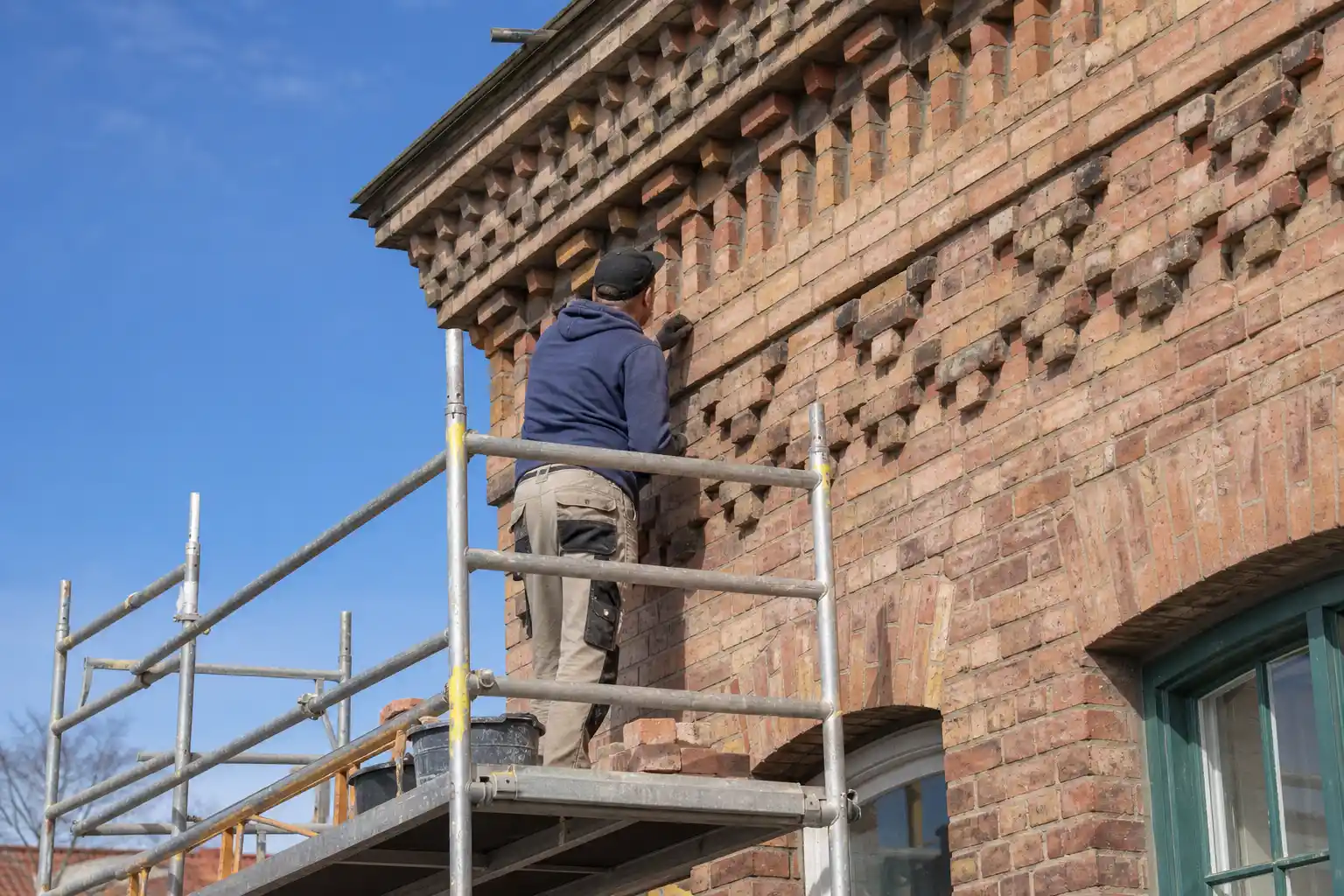 Mönstermurad tegelfasad på ett hus på Öster i Landskrona med murare på ställning