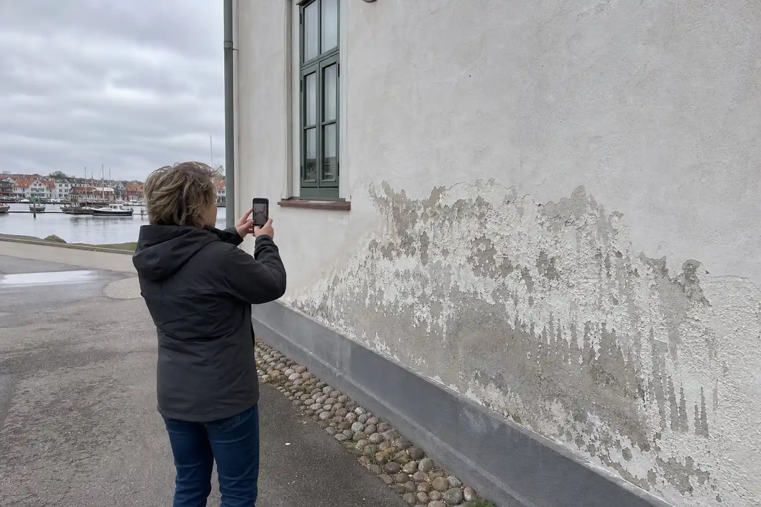 Husägare i Trelleborg fotograferar saltskador på en putsad fasad nära hamnen