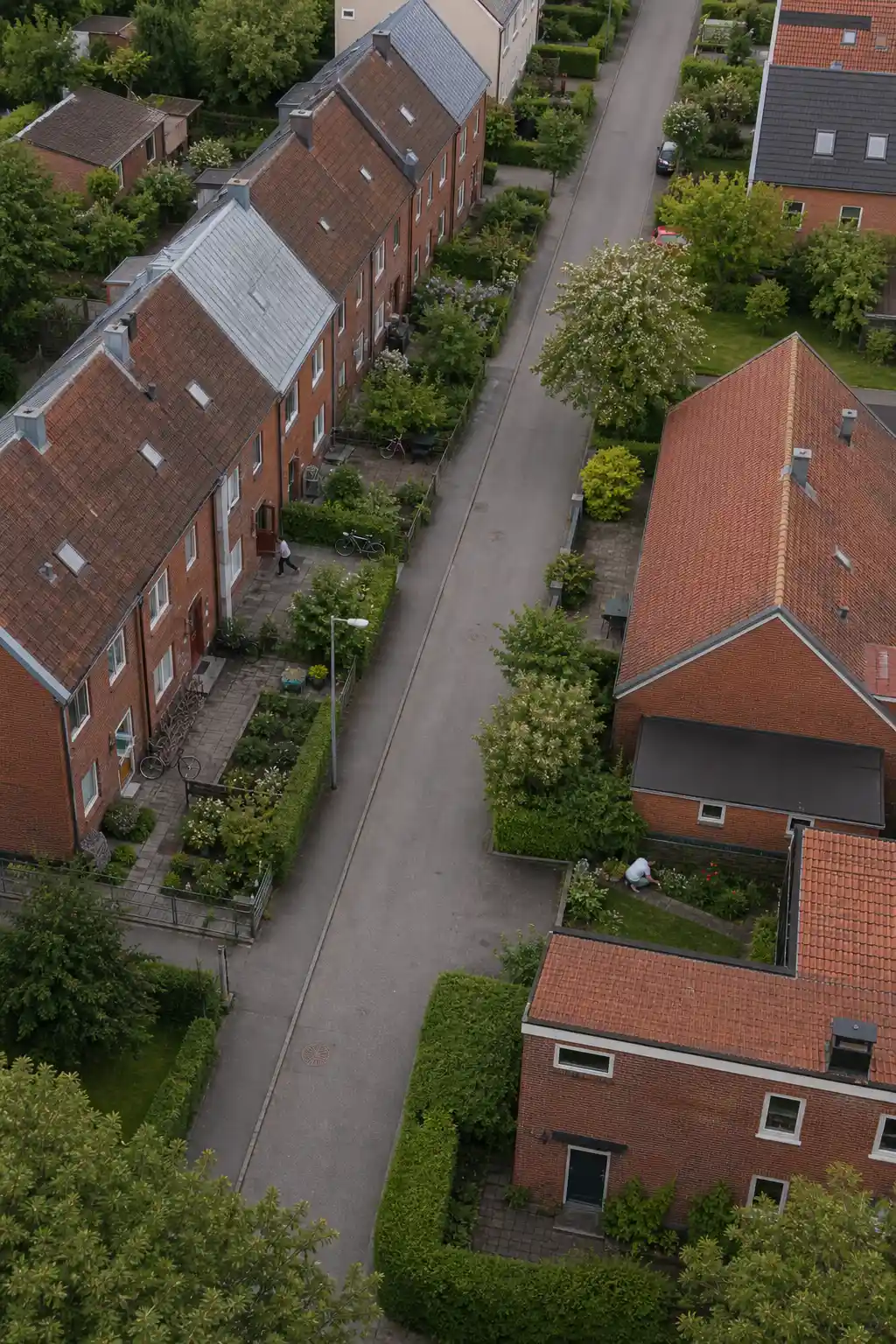 Flygfoto över ett svensk småstad kvarter med radhus, trädgårdar och en lugn gata på en vardag.