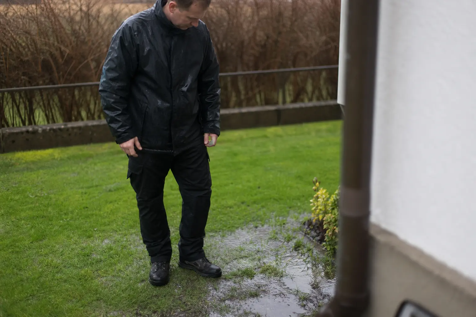 Plåtslagare synar vattnet som blivit stående vid stupröret efter ett regn i Kristianstad