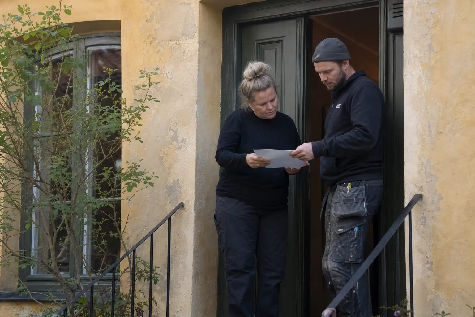 Husägare och plåtslagare går igenom en offert i dörren till ett gammalt stadshus i Ystad