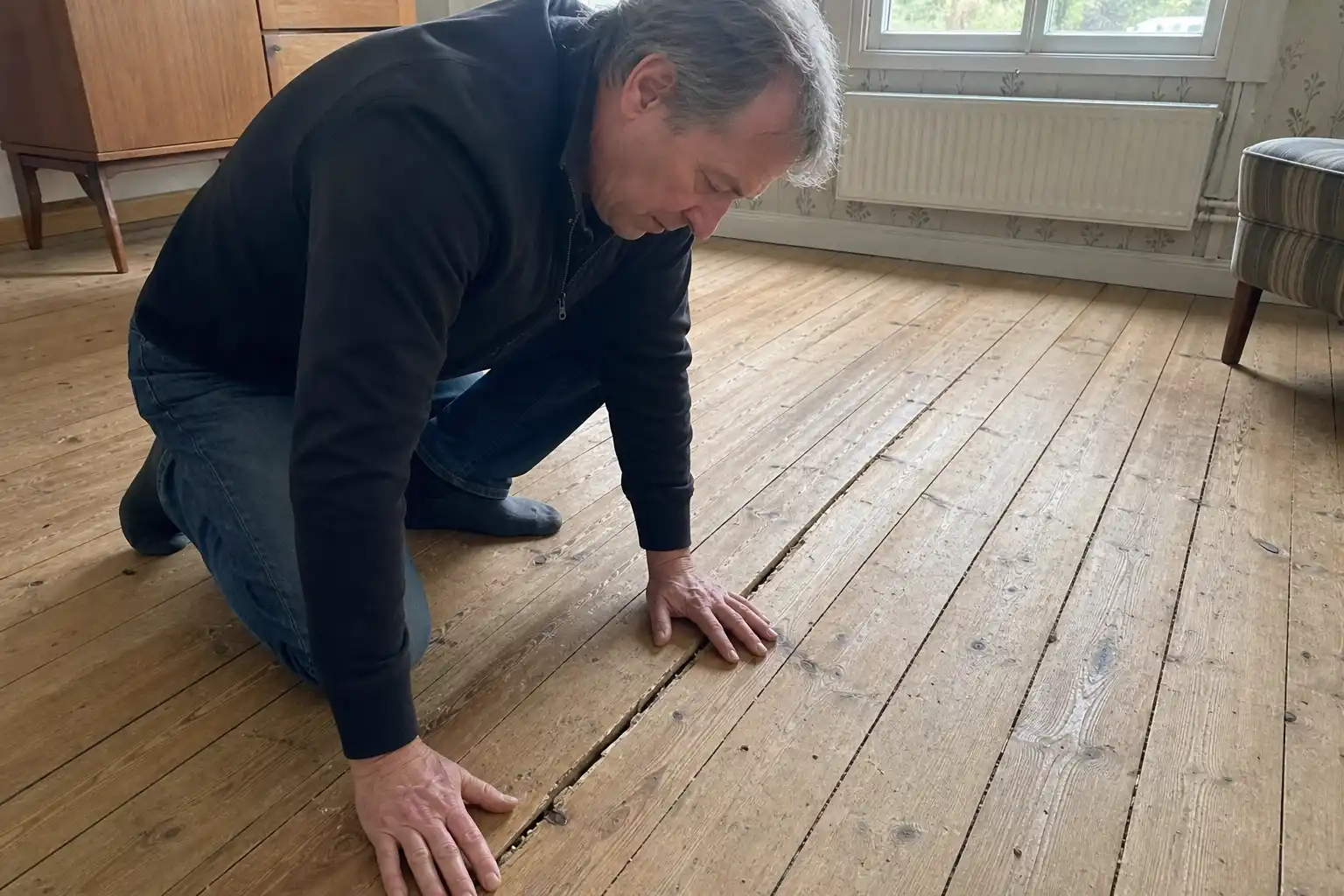 Husägare inspekterar knarrigt trägolv i 1960-talsvilla i Lund